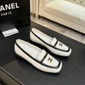 Chanel CC Logo Bicolor Leather Loafers in cream and black displayed on a dark surface next to Chanel box