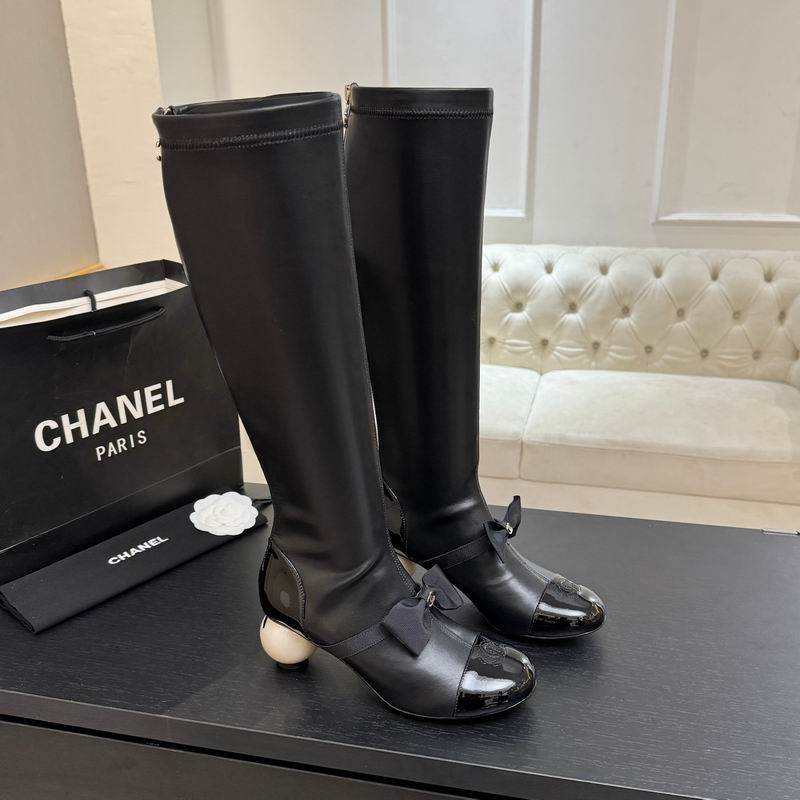 Chanel knee-high stretch boots in black with camellia cap toe and pearl heel, displayed with Chanel Paris shopping bag